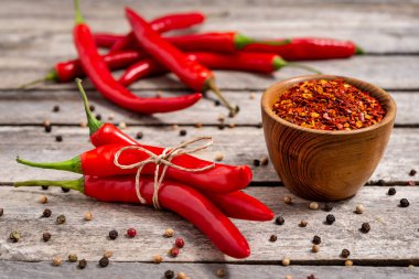 Eski masada ezilmiş kırmızı biberli ahşap kase ve taze kırmızı biber. Seçici odak.