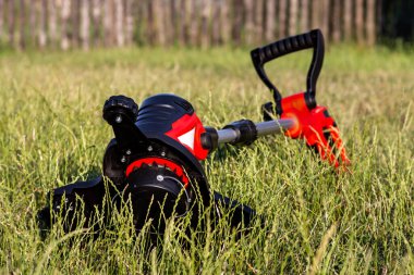 Güneşli bir günde bahçedeki çimleri biçmek için elektrikli budama makinesi. Seçici odak.