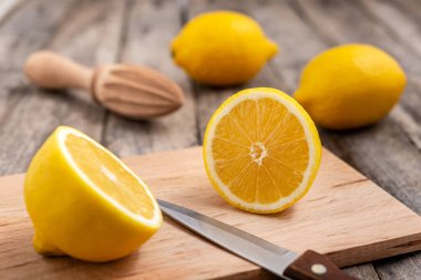 Tahta kesme tahtasındaki bıçakla kesilmiş taze limon. Seçici odak.