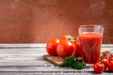 Bir bardak lezzetli domates suyu ve ahşap masa üzerinde metin için fotokopi alanı olan taze domatesler. Seçici odak.