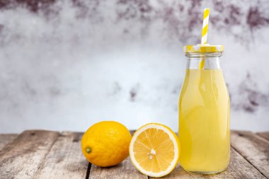 Köy ahşap masada saman ve limon dilimli bir şişe soğuk limonata. Seçici odak.