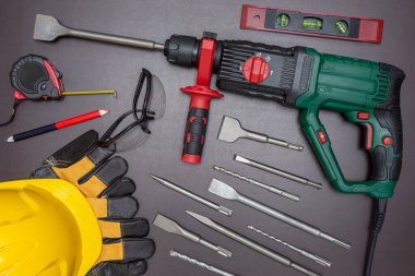 Üzerinde aksesuar ve koruyucu ekipman bulunan çekiç matkabı çalışma masasında..