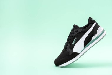 Obrenovac, Serbia - July 09, 2025: Stylish black Puma sneaker on a pastel green background with copy space for text.