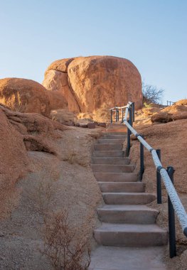 Namibya Çölü, binlerce yıldır doğal süreçler tarafından şekillendirilen dağınık kahverengi taşlara ve engebeli kaya oluşumlarına ev sahipliği yapar. Bu özellikler etrafındaki altın kumlarla keskin bir tezat oluşturarak kendine özgü bir çöl manzarası yaratır.
