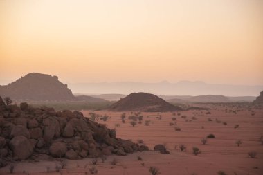 Namibya Çölü, binlerce yıldır doğal süreçler tarafından şekillendirilen dağınık kahverengi taşlara ve engebeli kaya oluşumlarına ev sahipliği yapar. Bu özellikler etrafındaki altın kumlarla keskin bir tezat oluşturarak kendine özgü bir çöl manzarası yaratır.