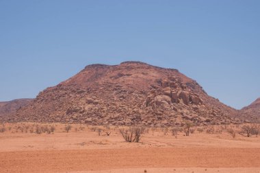 Namibya Çölü, binlerce yıldır doğal süreçler tarafından şekillendirilen dağınık kahverengi taşlara ve engebeli kaya oluşumlarına ev sahipliği yapar. Bu özellikler etrafındaki altın kumlarla keskin bir tezat oluşturarak kendine özgü bir çöl manzarası yaratır.