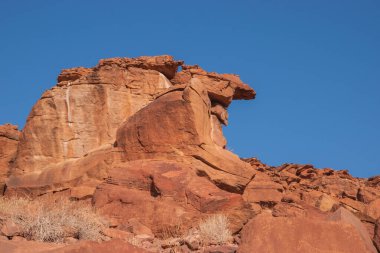 Namibya Çölü, binlerce yıldır doğal süreçler tarafından şekillendirilen dağınık kahverengi taşlara ve engebeli kaya oluşumlarına ev sahipliği yapar. Bu özellikler etrafındaki altın kumlarla keskin bir tezat oluşturarak kendine özgü bir çöl manzarası yaratır.