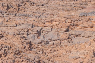Namibya çölü, binlerce yıldır doğal süreçler tarafından şekillendirilen dağınık gri taşlara ve engebeli kaya oluşumlarına ev sahipliği yapmaktadır. Bu özellikler etrafındaki altın kumlarla keskin bir tezat oluşturarak kendine özgü bir çöl manzarası yaratır.