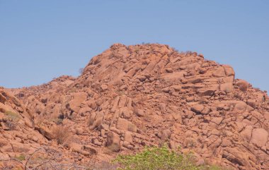 Namibya Çölü, binlerce yıldır doğal süreçler tarafından şekillendirilen dağınık kahverengi taşlara ve engebeli kaya oluşumlarına ev sahipliği yapar. Bu özellikler etrafındaki altın kumlarla keskin bir tezat oluşturarak kendine özgü bir çöl manzarası yaratır.