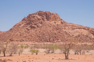 Namibya Çölü, binlerce yıldır doğal süreçler tarafından şekillendirilen dağınık kahverengi taşlara ve engebeli kaya oluşumlarına ev sahipliği yapar. Bu özellikler etrafındaki altın kumlarla keskin bir tezat oluşturarak kendine özgü bir çöl manzarası yaratır.