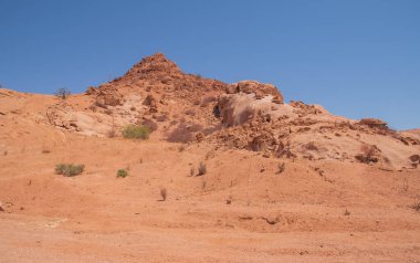 Namibya Çölü, binlerce yıldır doğal süreçler tarafından şekillendirilen dağınık kahverengi taşlara ve engebeli kaya oluşumlarına ev sahipliği yapar. Bu özellikler etrafındaki altın kumlarla keskin bir tezat oluşturarak kendine özgü bir çöl manzarası yaratır.