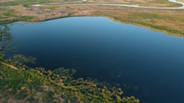 AERİAL. River valley. Gün batımında güzel doğa. Altın saat. Ovanın içinden dolambaçlı bir nehir akıyor. Dron ve kuadrokopterden ateş ediliyor. İnanılmaz manzaranın havadan görünüşü.