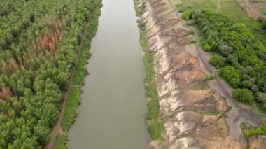 Nehir ormanın içinden akar. Clay River Bankası. Yüksek bir uçurum. Nehirde çamurlu su. Suyun etrafındaki yeşil orman. Dron ve kuadrokopterden ateş ediliyor. İnanılmaz manzaranın havadan görünüşü.