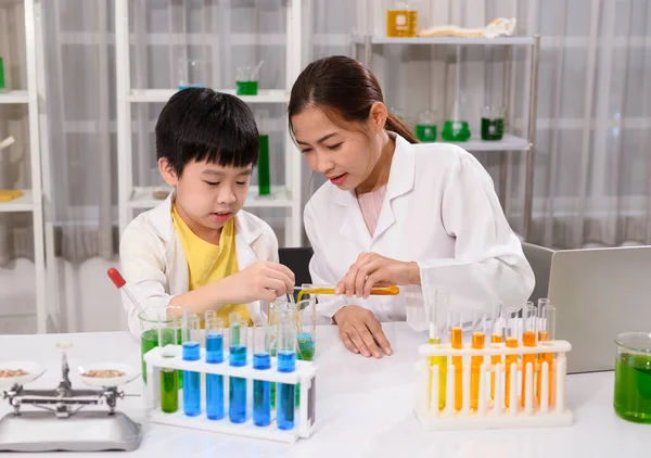 Science teacher testing a chemical experiment with child students in laboratory classroom