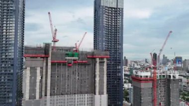 Gökdelenin tepesinde şehir arkaplanlı 4K kule vinçleri