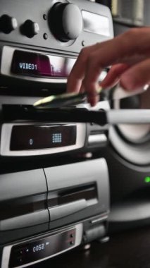 Bir adamın dikey görüntüsü 4K Klasik stereo teypten CD yerleştirip oynatılıyor