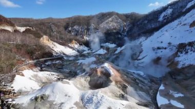 Japonya 'nın Hokkaido kentindeki Noboribetsu şehrindeki Jigokudani Cehennem Vadisi' nde jeotermal buhar bacalarının 4K hava görüntüsü.