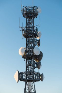 Mavi gökyüzü arka planında uydu anteni olan yakın çekim telekomünikasyon kulesi