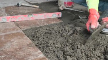 4K İnşaat işçileri döşeme döşemeleri için zemine çimento yapıştırıcı sürerler