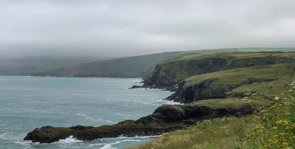 Port Gaverne, Cornwall, İngiltere yakınlarında sisli ve yağmurlu bir günde Cornish sahili manzarası.