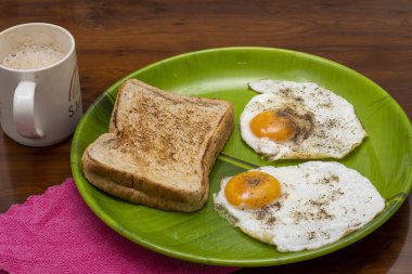 Tost ekmeğinin yakın plan resmi ve yeşil tabakta çay eşliğinde güneşli yumurta.