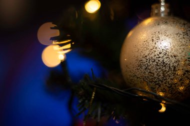 Altın topları ve koyu arkaplanda bokeh olan Noel ağacına yakın çekim. Tatil tasarımı için kopyalama alanı olan arkaplan.