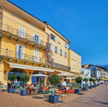 ASCONA, SWitzERLAND - 28 Mart 2022 'de Ascona' da, göl kenarı Piazza Giuseppe Motta 'daki antika evler boyunca uzanan restoranların verandaları