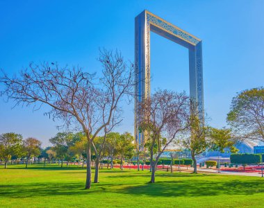 DUBAI, BAE - 6 Mart 2020: Zarif Dubai Frame, Zabeel Park 'ın yemyeşil ağaçlarının arkasında, 6 Mart' ta Dubai