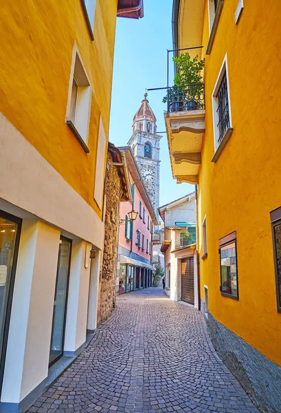 St. Peter ve St. Paul Kilisesi 'nin küçük dükkanları, kafeleri ve uzun taş saat kulesiyle eski kasabadaki dar yaya sokağı gökyüzüne hakim, Ascona, İsviçre