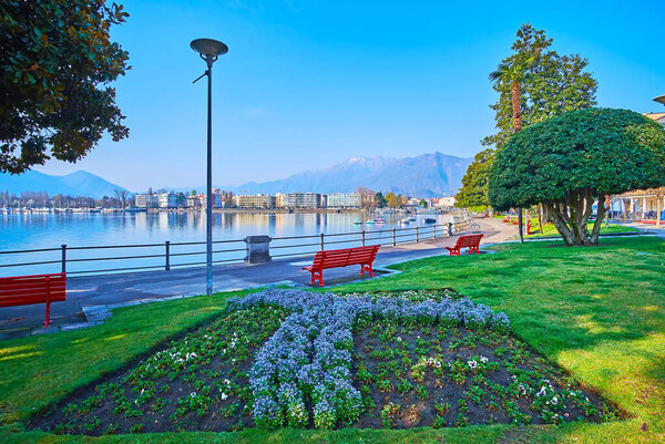 Embankment of Lake Maggiore, decorated with lush green park with blooming flower beds and topiary trees, Locarno, Switzerland