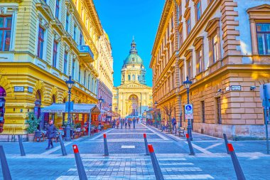 BUDAPEST, HUNGARY - 2 Mart 2022 'de Budapeşte' de arka planda restoranlar ve barlar ve St. Stephen 's Katedrali' nin bulunduğu yaya turizm alanı