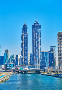 DUBAI, BAE - 6 Mart 2020: Dubai Su Kanalı ve Dubai Şelale Köprüsü 'nün arkasında görülen fütürist cam JW Marriot Kuleleri