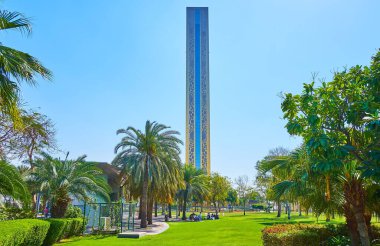 Palmiyeleri, çalı çalıları, yeşil çimenleri ve arka planda Dubai Frame 'in yan duvarı olan güzel Zabeel Parkı, Dubai, BAE