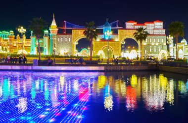 DUBAI, BAE - 6 Mart 2020: Küresel Dubai Köyü 'nün göletindeki su altı LED ekranındaki ışık gösterisi, arka planda farklı ülkelerin pavyonları, 6 Mart' ta Dubai 'de