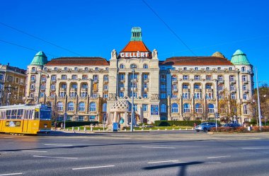 BUDAPEST, HUNGARY - 22 Şubat 2022: Gellert Meydanı, Gellert Oteli ve Termal Hamamlar 'ın etkileyici binasına karşı hızlı sabah trafiği ile Budapeşte' de 22 Şubat 'ta