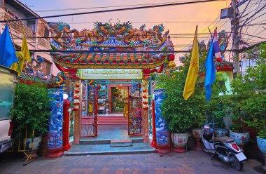 Ornate paifang gate of Pung Thao Kong Shrine with lush green plants in the foreground, Chiang Mai, Thailand