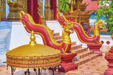 The scenic red statues of Mom aquatic mythical creatures, decorated with gilt, located in front of the viharn in Wat Ratcha Monthian, Chiang Mai, Thailand
