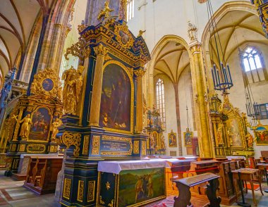 PRAGUE, CZECHIA - MARCH 11, 2022: The line of old icons in beautiful golden frames along the nave in Church of Our Lady before Tyn, on March 11 in Prague, Czechia