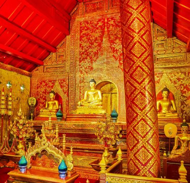 CHIANG MAI, THAILAND - MAY 3, 2019: The ornate red prayer hall of Viharn Lai Kham, decorated with fine gilt patterns and golden statues of Buddha, Wat Phra Singh, on May 3 in Chiang Mai