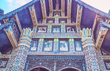 The teakwood gable end of the Viharn of Wat Lok Moli, decorated with relief stucco ornaments and colored glass, Chiang Mai, Thailand