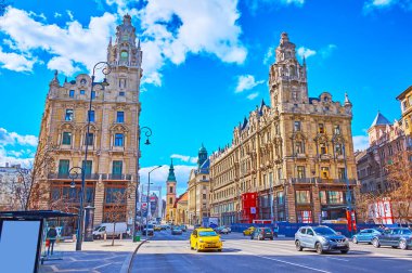 BUDAPEST, HUNGARY - FEB 22, 2022: The fast traffic on Lajos Kossuth Street with a view on iconic Clotilde Palaces against the bright blue sky, on Feb 22 in Budapest