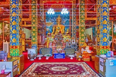 CHIANG MAI, THAILAND - MAY 3, 2019: Interior of the viharn of Wat Dap Phai with golden images of Buddha, blue and green pillars, covered with gilt floral patterns, on May 3 in Chiang Mai, Thailand