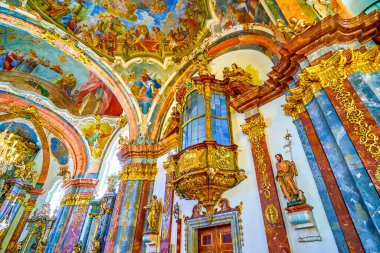 PRAGUE, CZECHIA - MARCH 11, 2022: Richly decorated interior of Church of the Nativity in Loreta with colorful frescoes, gilden fretwork and sculptures, on March 11 in Prague, Czechia