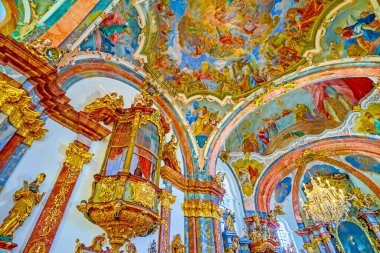 PRAGUE, CZECHIA - MARCH 11, 2022: Golden fretwork and moulding, sculptures and colorful frescoes in prayer hall of Church of the Nativity in Loreta, on March 11 in Prague, Czechia