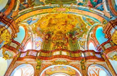 PRAGUE, CZECHIA - MARCH 11, 2022: The pipe organ in surrounding of colorful murals on the balcony of Church of the Nativity in Loreta complex, on March 11 in Prague, Czechia