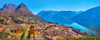Panorama of Castello from the top of the hill with a view on Lake Lugano, tile roofs and rocky Lugano Prealps with peaks of Monte dei Pizzoni and Monte Bronzone, Valsolda, Italy clipart
