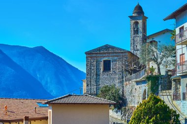 The tall bell tower of Sant'Ambrogio Church, located on the Alpine slope in Albogasio Superiore (upper town), Valsolda, Lombardy, Italy