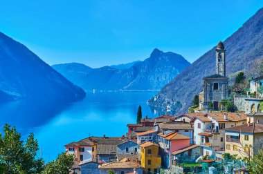 The picturesque mountain village of Albogasio Superiore observes mirror-like Lake Lugano and Lepontine Alps around it, Valsolda, Italy
