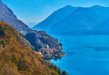 The picturesque mountain scenery with azure Lake Lugano and tiny San Mamete village, located at lakefront, Valsolda, Italy