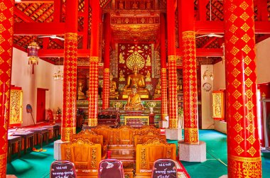 CHIANG MAI, THAILAND - MAY 3, 2019: The red gamma interior of the Viharn in Wat Pan Ping with slender columns and walls, covered with fine gilt patterns, Chiang Mai, Thailand